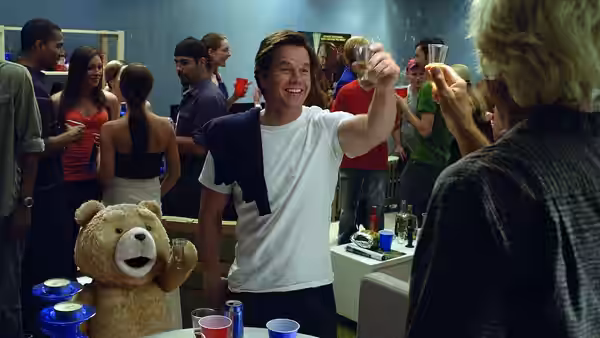John Bennett (Mark Wahlberg) raises a glass at a party beside Ted