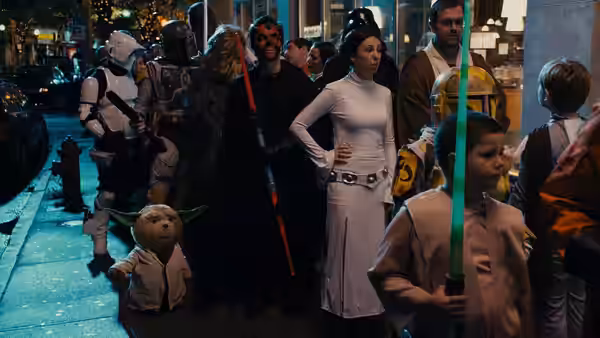 Ted in a Yoda costume walks among costumed revelers on a crowded street