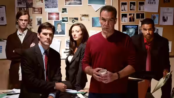Agents gathered in an office with photos pinned to a bulletin board