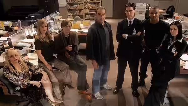 Team members posing together inside a cluttered police department bullpen