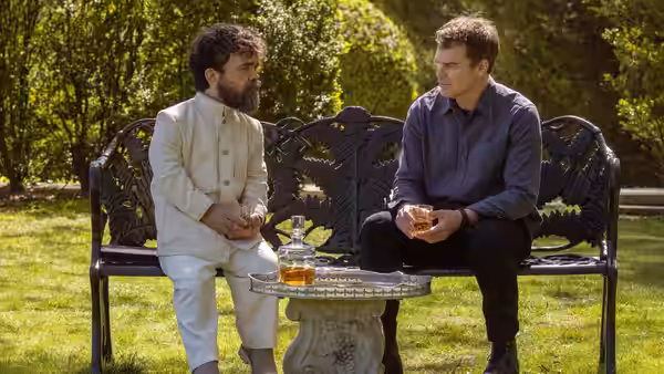 Dexter Morgan (Michael C. Hall) seated on a bench beside a bearded man
