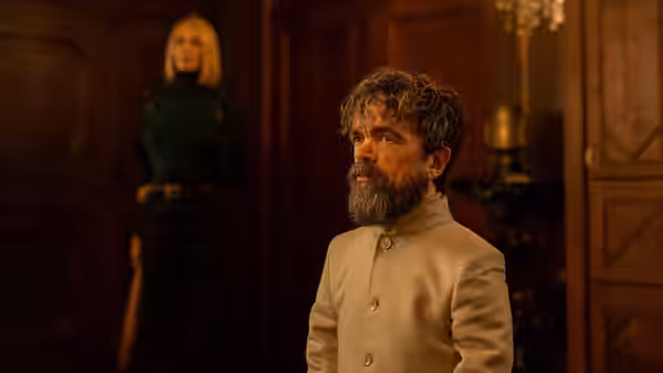 Bearded man in white jacket standing in a wood-panelled room