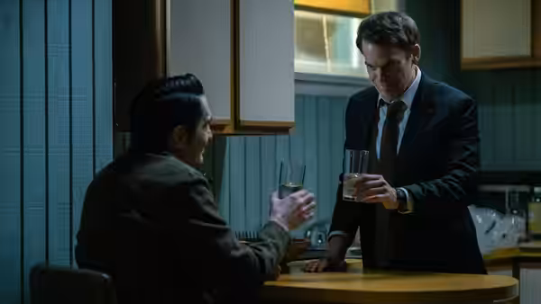 Dexter Morgan (Michael C. Hall) toasting with glasses at a round table