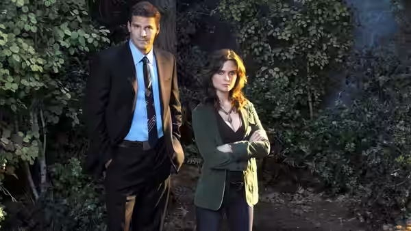Booth (David Boreanaz) and Brennan (Emily Deschanel) stand in a wooded area