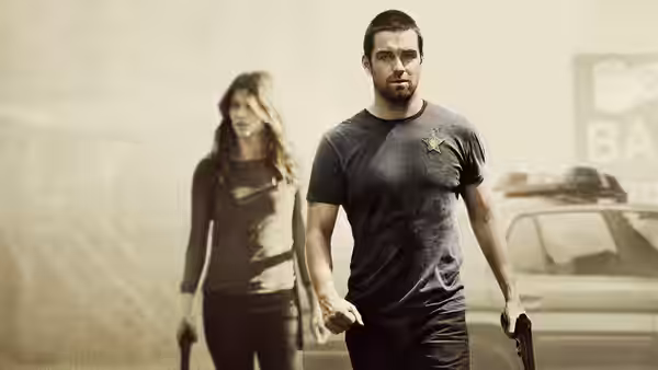 Lucas Hood (Antony Starr) and Carrie Hopewell (Ivana Miličević) holding guns near a car