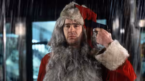 Louis Winthorpe III (Dan Aykroyd) dressed as Santa holding a gun in the rain