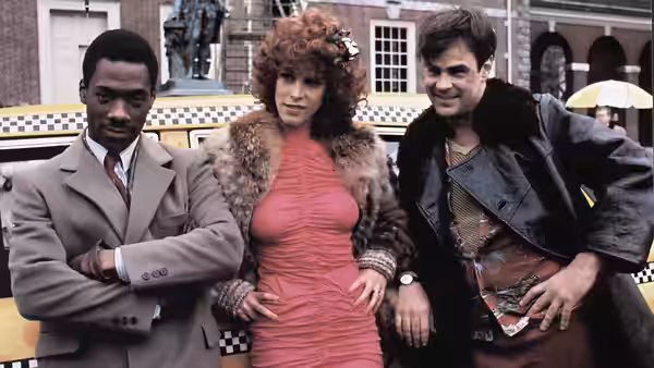 Billy Ray Valentine (Eddie Murphy), Ophelia (Jamie Lee Curtis) and Louis Winthorpe III (Dan Aykroyd) by a taxi