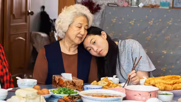 Nai Nai (Zhao Shuzhen) and Billi (Awkwafina) at a laden dinner table
