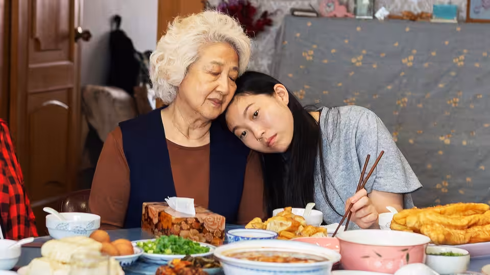 Nai Nai (Zhao Shuzhen) and Billi (Awkwafina) at a laden dinner table