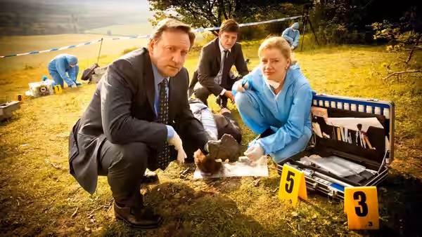 Detectives examining evidence at a rural outdoor crime scene