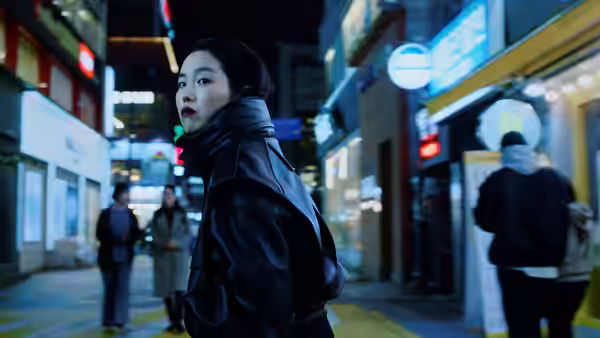 Freddie (Ji-min Park) in a black leather jacket turns on a neon-lit nighttime street