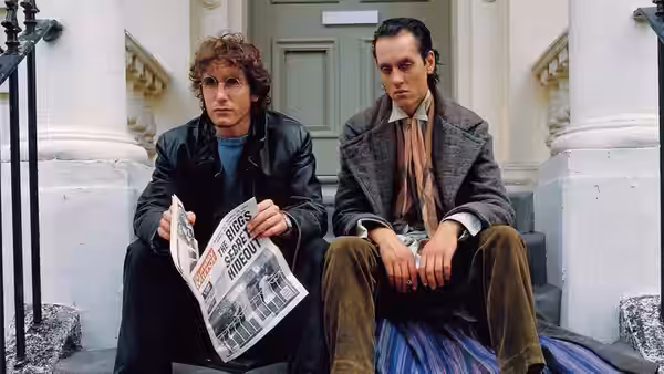 Withnail (Richard E. Grant) and Marwood (Paul McGann) sitting on steps outside a house
