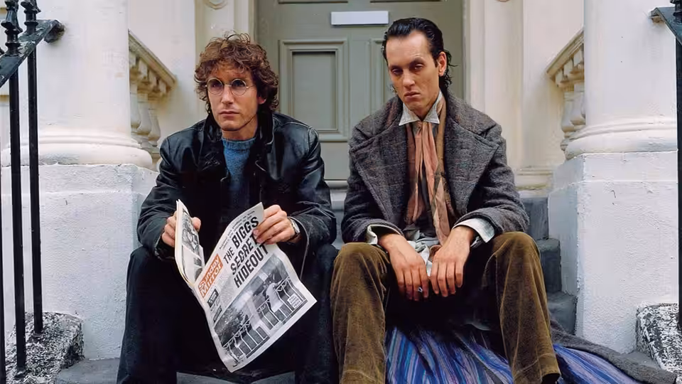 Withnail (Richard E. Grant) and Marwood (Paul McGann) sitting on steps outside a house