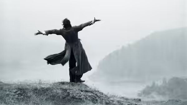 Withnail (Richard E. Grant) standing with arms outstretched on a misty hillside