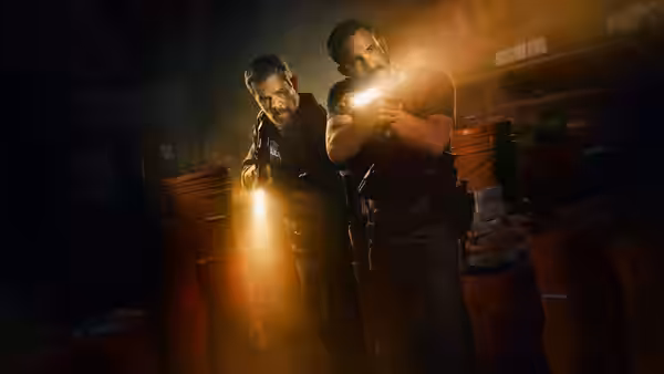 Matt Damon and Ben Affleck advancing through a dark warehouse with flashlights