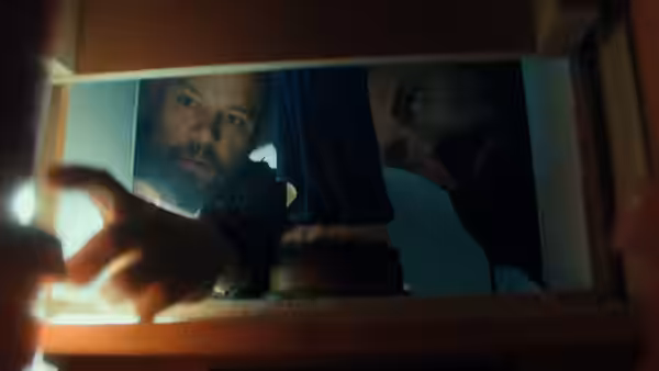 Matt Damon and Ben Affleck peering through a small window opening