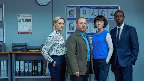 DI Max Arnold with three colleagues posing together in a station office