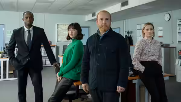 DI Max Arnold with three colleagues standing in a brightly lit police office