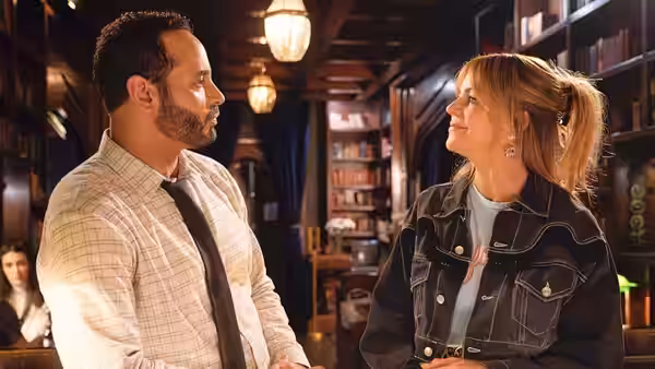Adam Karadec and Morgan Gillory face each other inside a dimly lit library