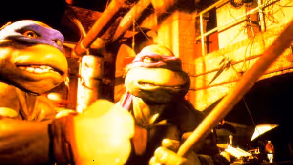 Two masked turtles hold weapons among pipes and machinery