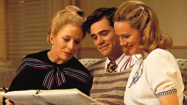 Truman Burbank (Jim Carrey) reading a book with two women on a sofa