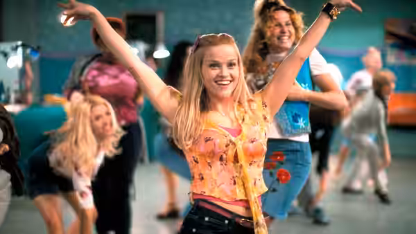 Elle Woods (Reese Witherspoon) dancing with arms raised in a salon