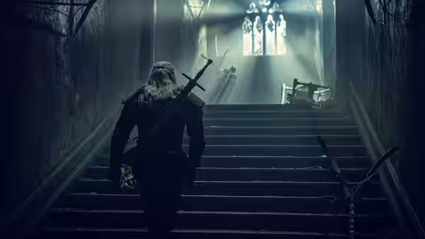 Geralt (Henry Cavill) ascending stone stairs in a dark corridor