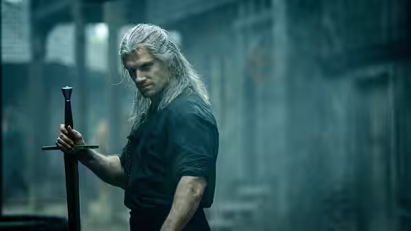 Geralt (Henry Cavill) holding a sword in ruined stone halls