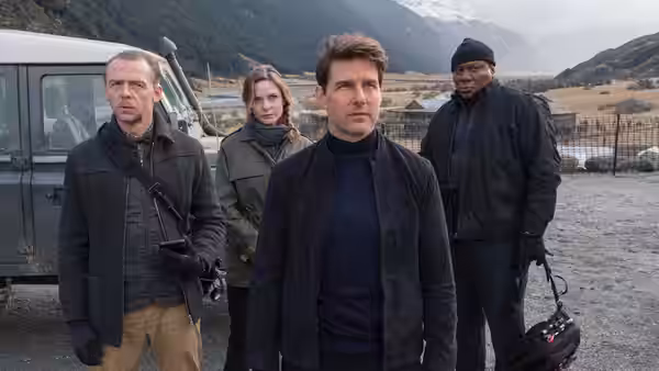 Ethan Hunt (Tom Cruise) standing with three teammates beside a vehicle in the mountains
