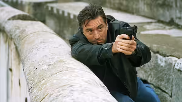 Sam (Robert De Niro) aiming a pistol over a stone ledge