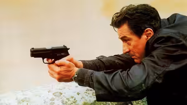 Sam (Robert De Niro) aiming a handgun from behind cover