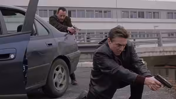 Vincent (Jean Reno) aiming a gun near Sam (Robert De Niro) by a car