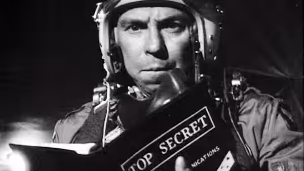 Major 'King' Kong (Slim Pickens) reading a top secret book while wearing flight helmet