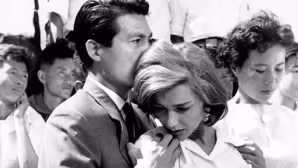 Lui (Eiji Okada) holds a distressed Elle (Emmanuelle Riva) amid a crowd