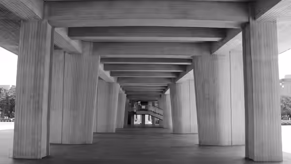An empty concrete colonnade recedes toward a distant building