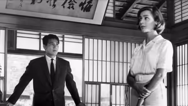 Lui (Eiji Okada) and Elle (Emmanuelle Riva) stand inside a Japanese building