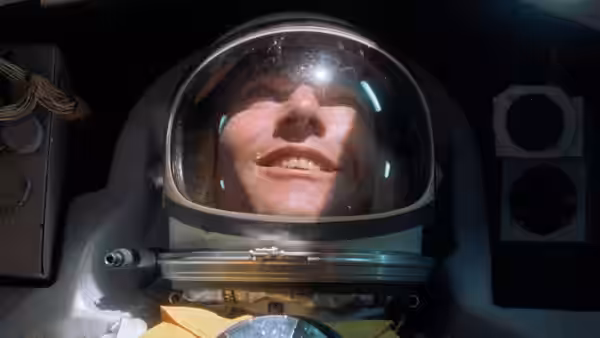 Astronaut smiles through helmet visor inside a spacecraft cockpit