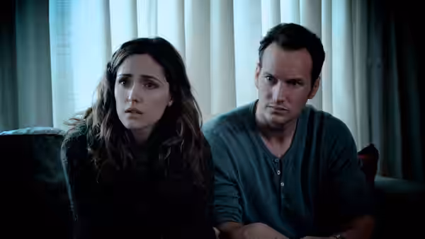 Renai Lambert (Rose Byrne) and Josh Lambert (Patrick Wilson) sit tensely together on a couch
