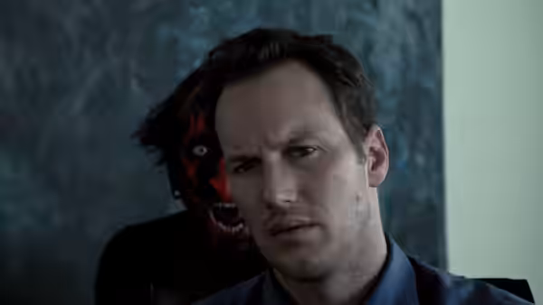 Josh Lambert (Patrick Wilson) stares ahead as a red-faced demon looms behind him