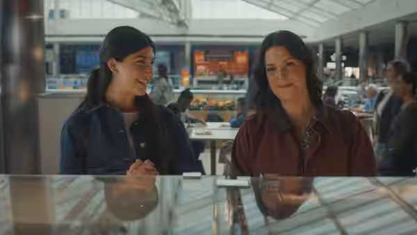 Young woman smiles while talking with an older woman at a table
