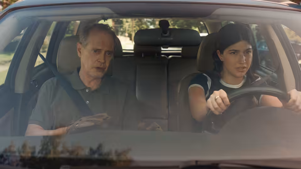 Steve Buscemi rides in a car driven by a young woman
