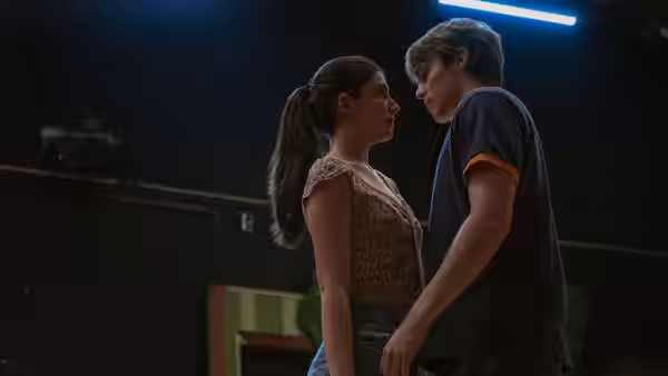 Young woman and young man stand face to face in a dark room