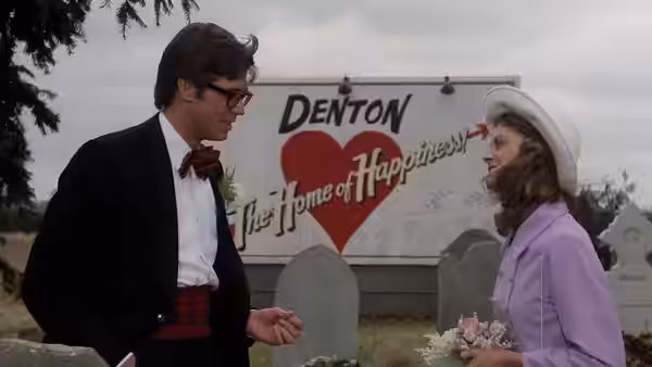 Brad Majors (Barry Bostwick) and Janet Weiss (Susan Sarandon) stand before the Denton sign in a graveyard