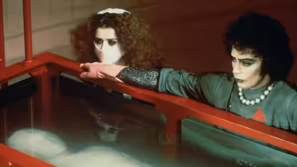 Dr. Frank-N-Furter (Tim Curry) and Magenta (Patricia Quinn) peer into a red-framed tank