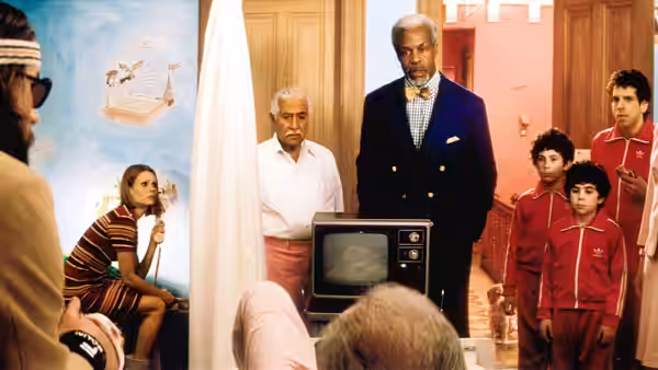 Several adults and children stand around an old television in a hallway