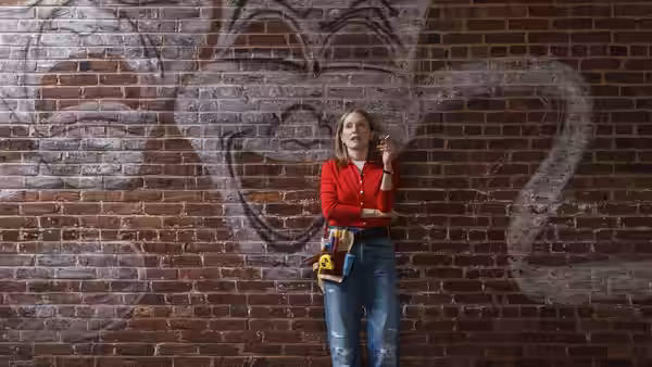 Mona (Julianne Moore) stands before graffiti-covered brick wall