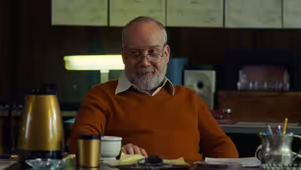 Jerry (Paul Giamatti) sits at desk with papers and coffee cup