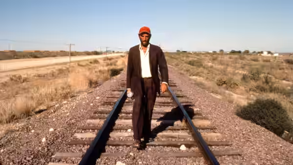 Travis (Harry Dean Stanton) walking along railway tracks in open country