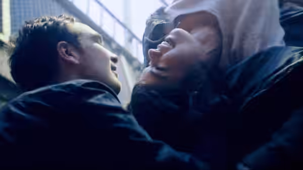 A man and woman lie on the ground looking at each other