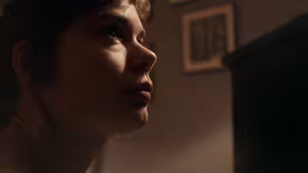 A woman looks to the side in profile in a dimly lit room